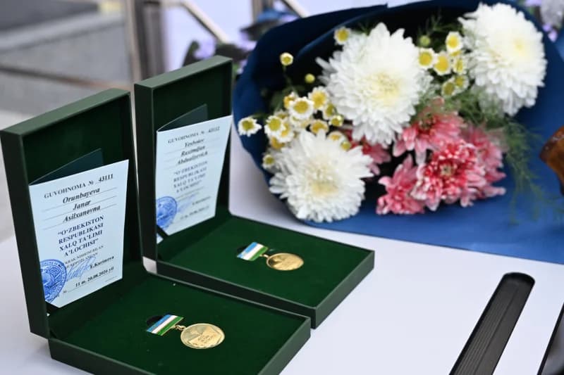 State awards and certificates in open boxes beside a bouquet of flowers
