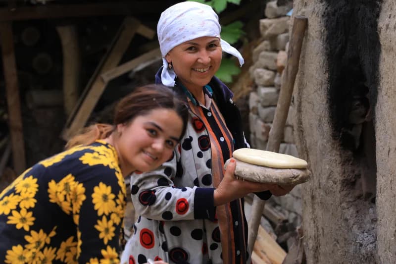 People baking traditional bread near an outdoor clay oven