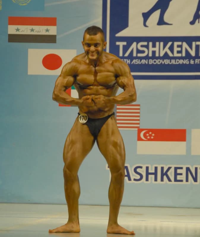 Бодибилдер позирует во время спортивных соревнований