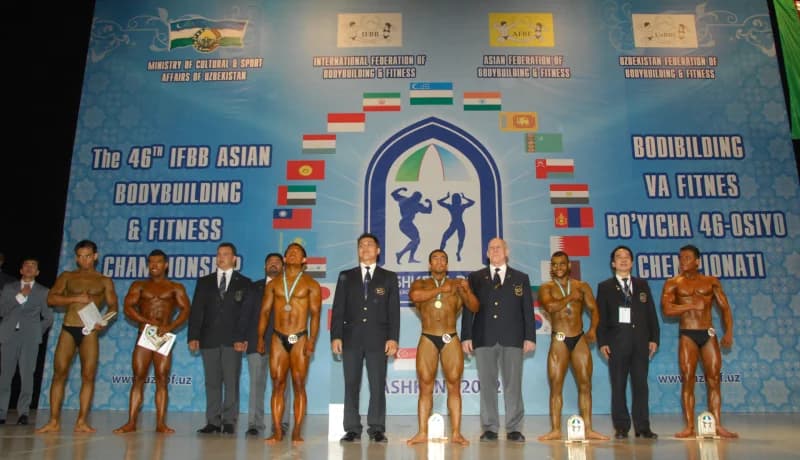 Bodybuilders and officials posing on stage at a championship event