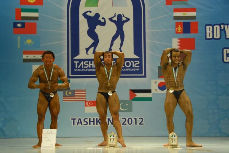 Bodybuilders posing with medals on stage