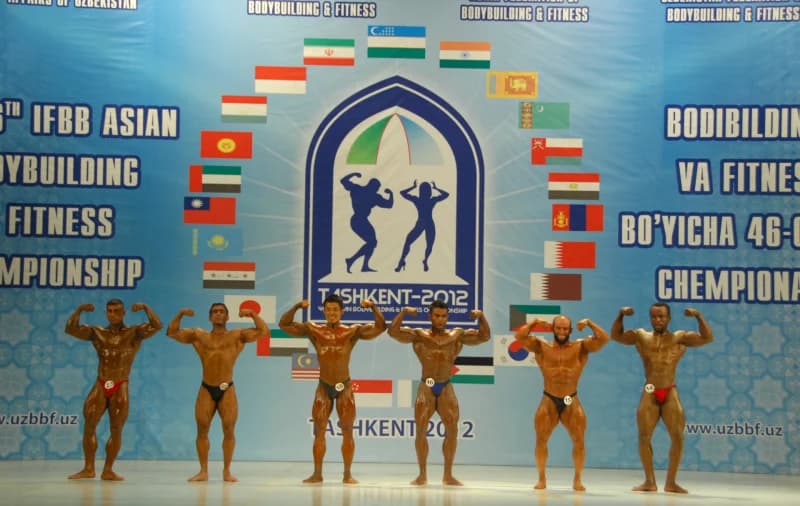 Bodybuilders pose on stage during competition
