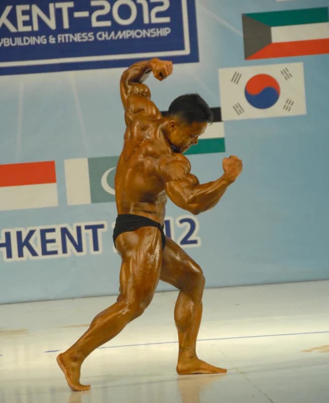 Спортсмен позирует на сцене во время бодибилдинга