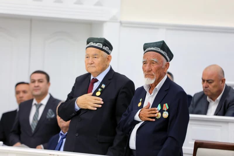 Seniors standing with hands on chests in an indoor gathering