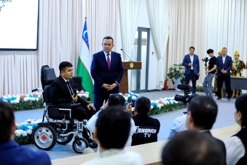Man speaking into microphone from wheelchair at conference