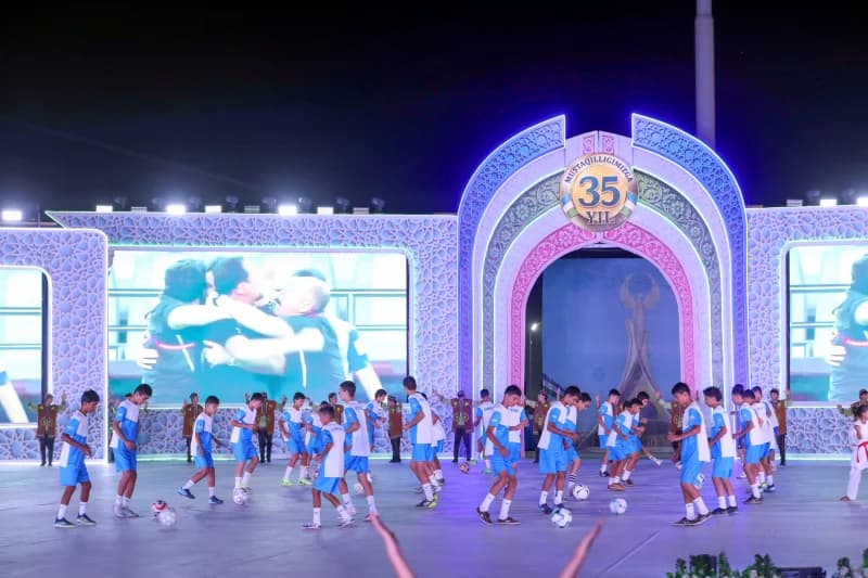 Young people performing with footballs on a stage at night