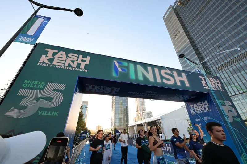 Runners cross the finish line under a large branded archway