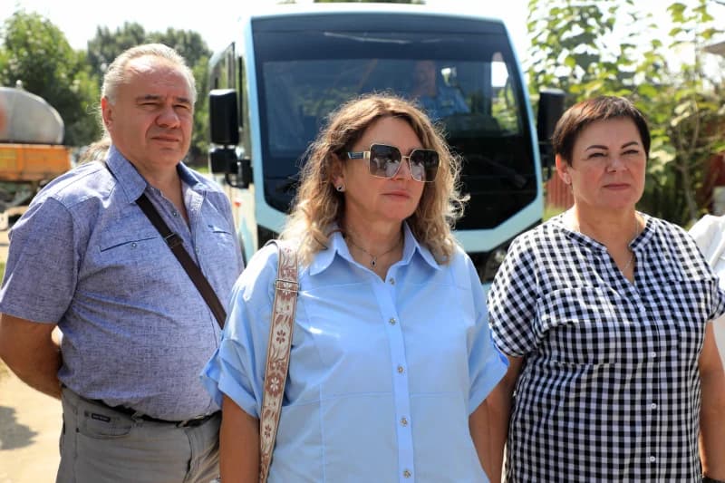 Three people standing outside near a bus