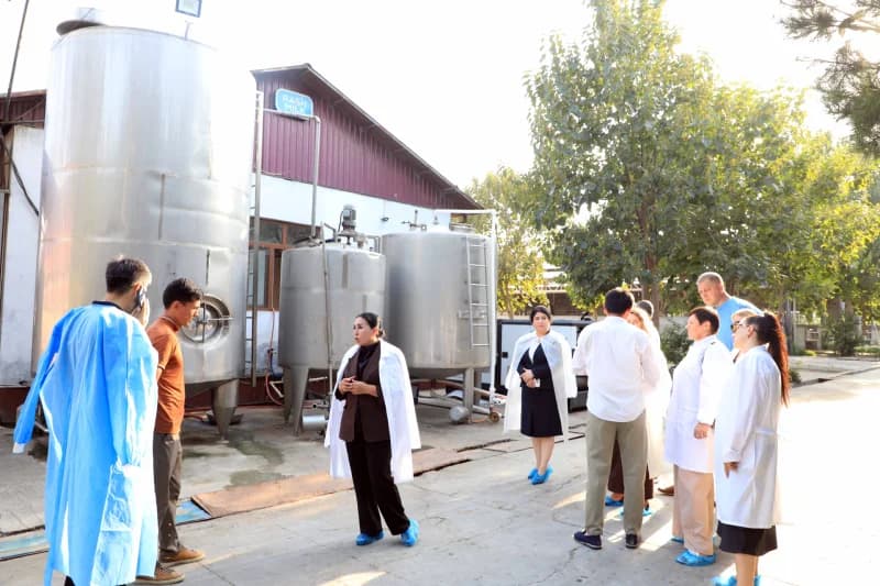 People gathered near industrial tanks at a production facility