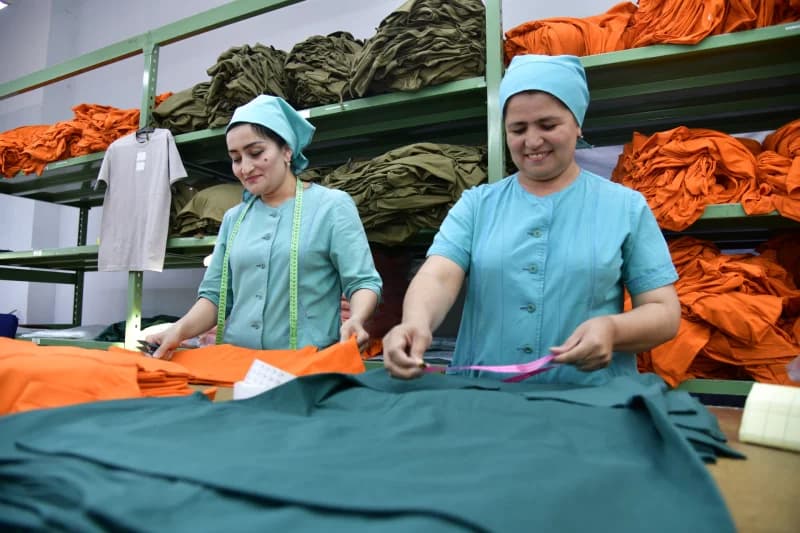Workers inspecting and measuring textiles at a factory
