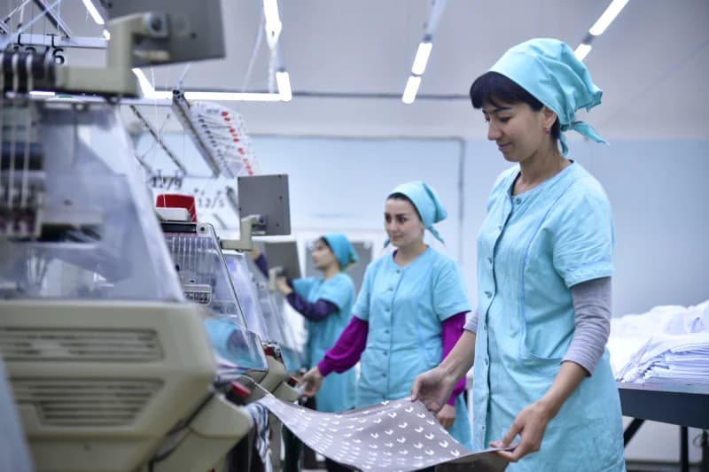 Workers operating textile machinery in a garment factory