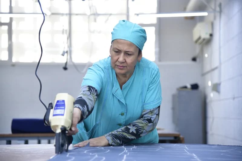 A woman working with a cutting machine in a workshop