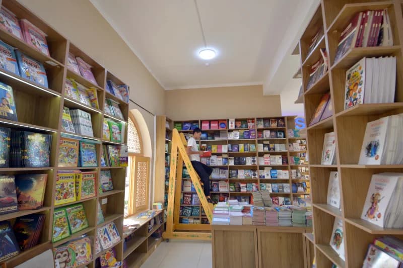 Person reading book on ladder in bookstore
