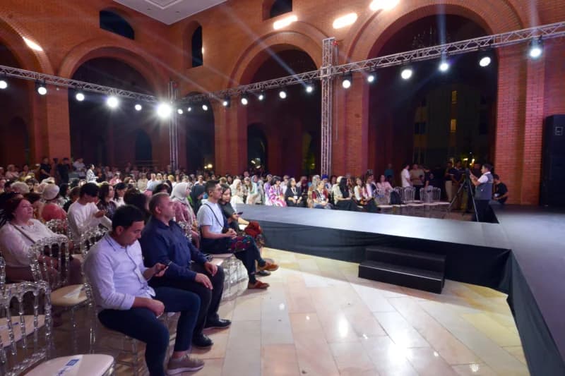 People seated inside a large brick hall with an elevated stage