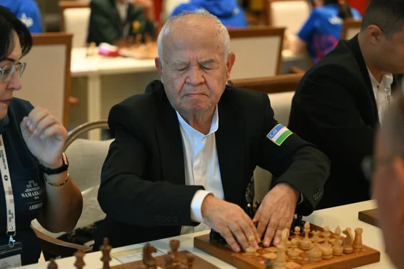 Пожилой мужчина играет в шахматы за столом