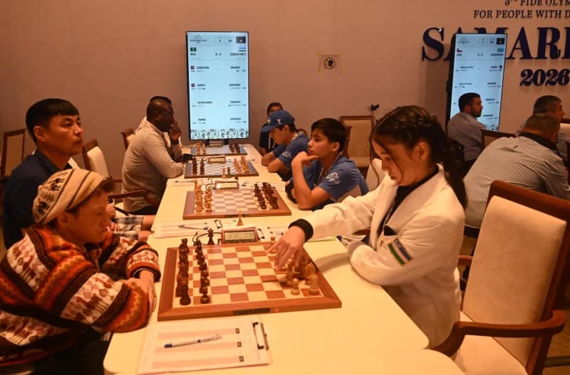 People playing chess at tables in a competition hall