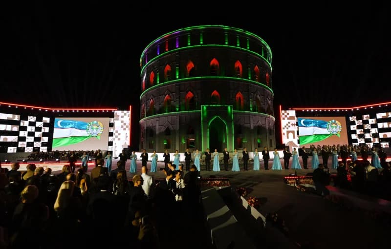People gathered at an illuminated evening event with screens and circular architecture
