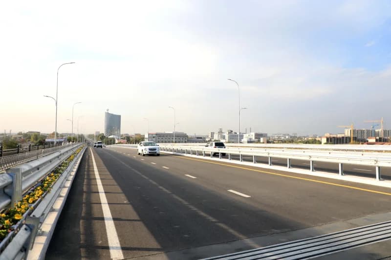 Cars drive on a multi-lane overpass with safety barriers