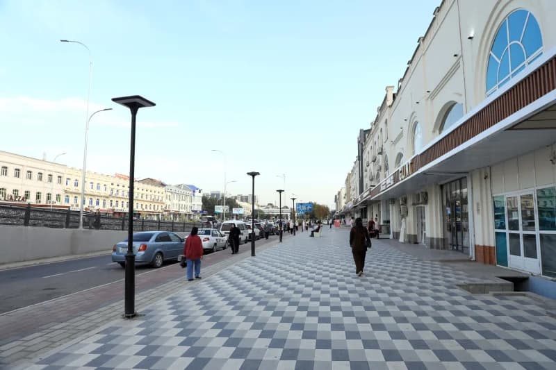 People walking on a tiled pedestrian sidewalk along a city street