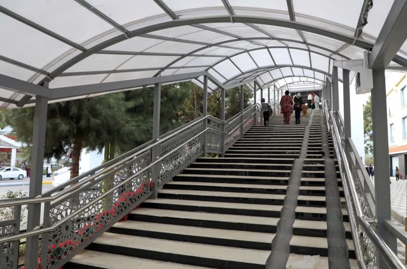 People walking up covered outdoor staircase with metal railings