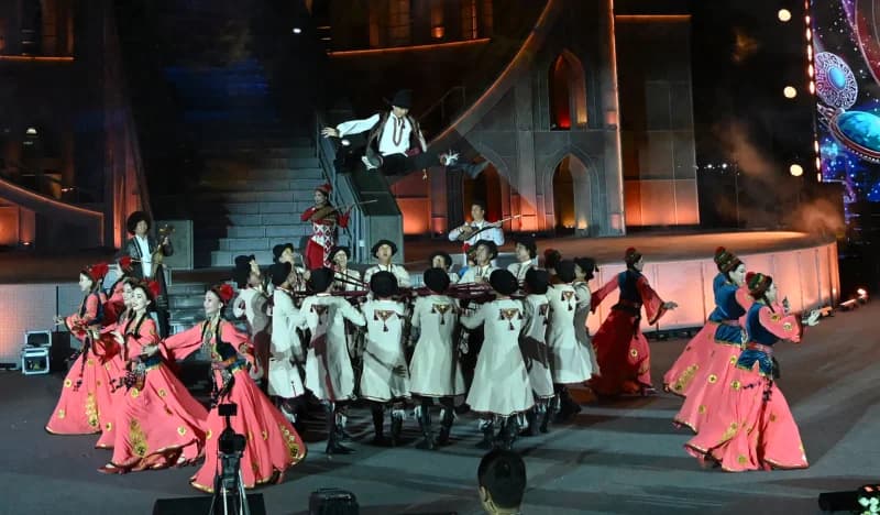 Performers in traditional clothing present a dance routine on an illuminated stage