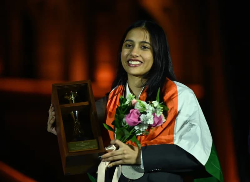 Smiling person holding trophy and flowers