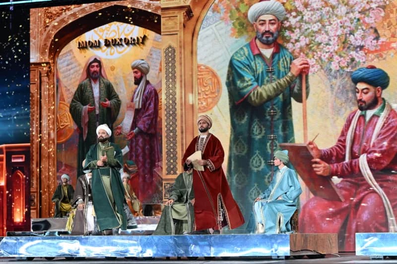 People in traditional historical costumes perform on stage in front of a large screen