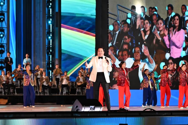 Performer singing on stage with dancers and musicians