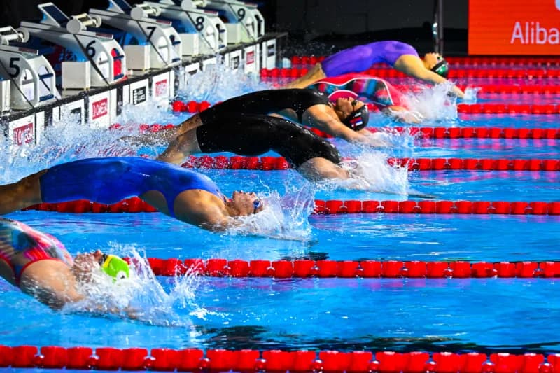 Swimmers in a backstroke race launching off starting blocks