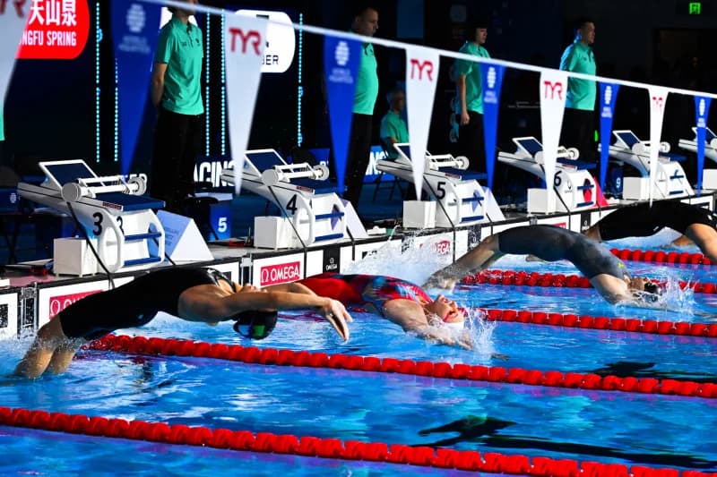 Swimmers dive from starting blocks into a pool