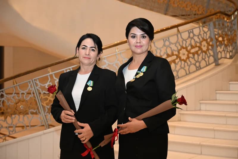 Two women standing with flowers and medals indoors