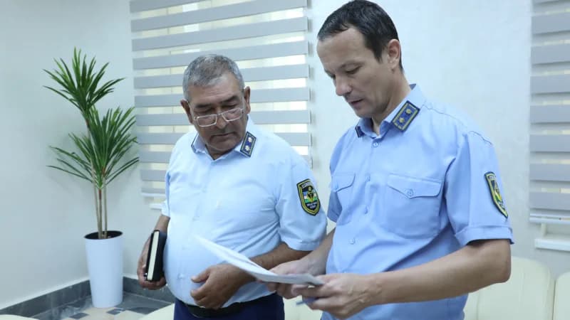Двое мужчин в голубой форме просматривают документы в помещении