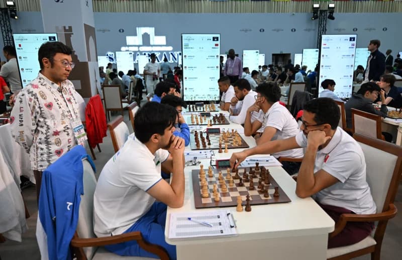 Competitors play chess matches at tables inside a large hall