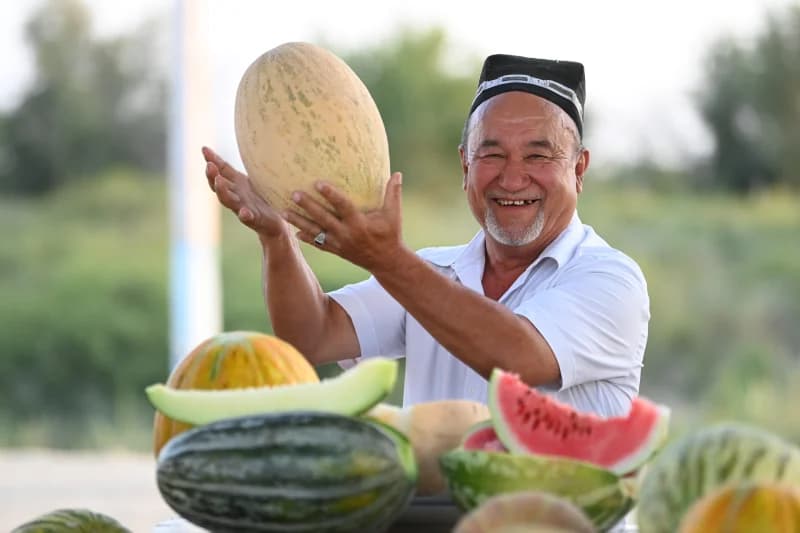 Smiling person holding a melon outdoors