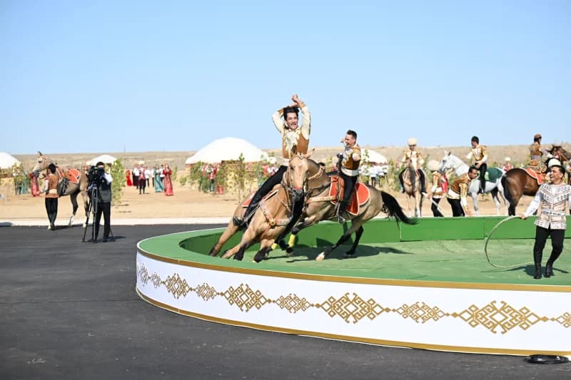 Performers riding horses in an arena during an outdoor event