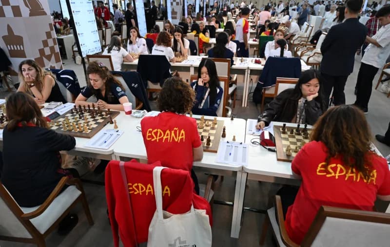 People playing chess at tables in a large hall