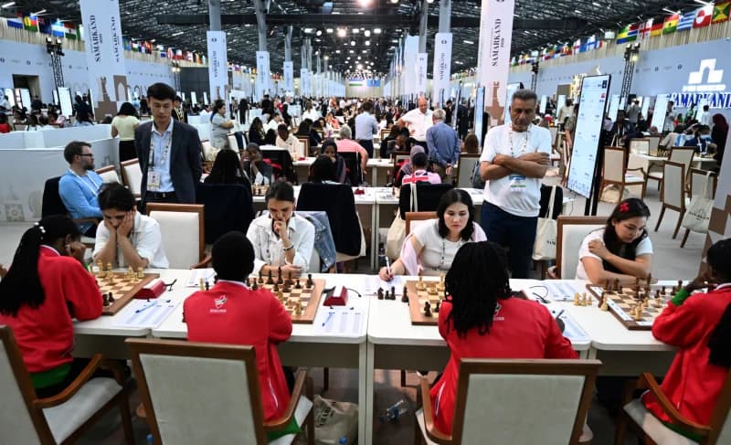 People playing chess at tables in a large hall