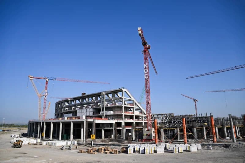 Construction site of a large concrete building with multiple cranes