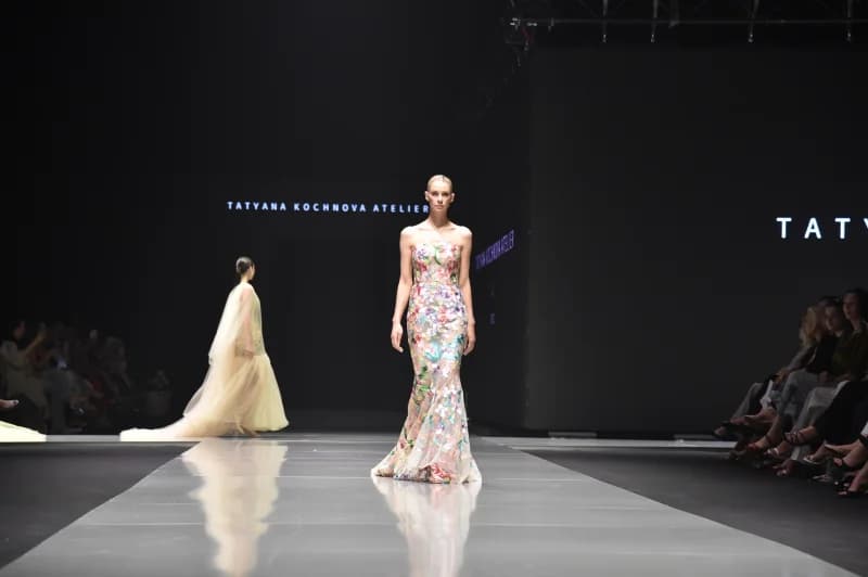 Models walk down a glossy runway at a fashion show