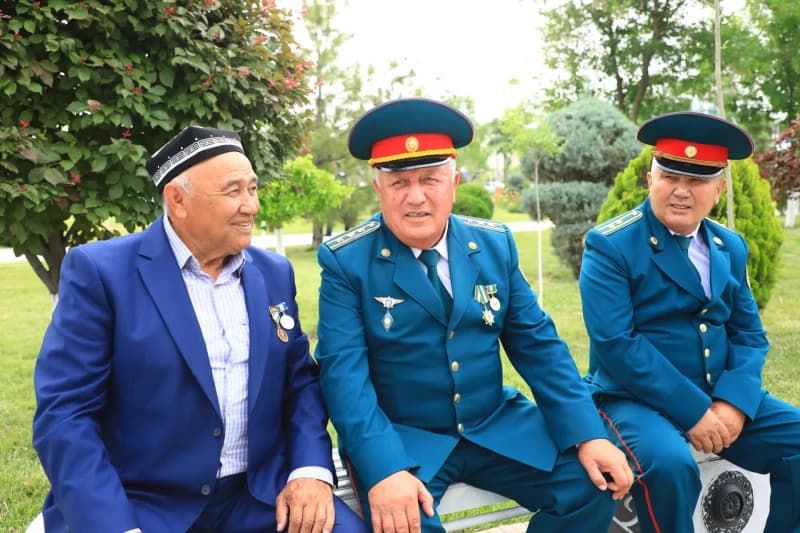 Трое мужчин сидят на скамейке на улице