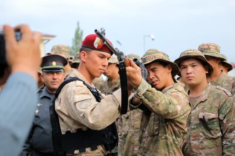 Люди в военной форме осматривают винтовку на улице