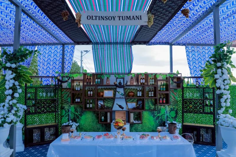 Exhibition booth displaying bottled goods and food under a decorated canopy