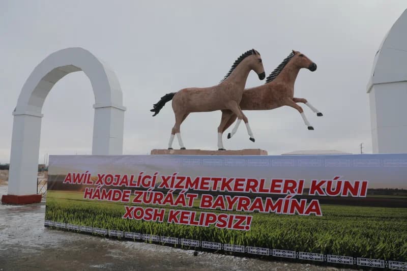 Statue of two horses and banner with visible text outdoors
