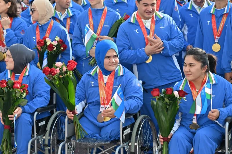 Group of athletes in blue tracksuits with medals and flowers