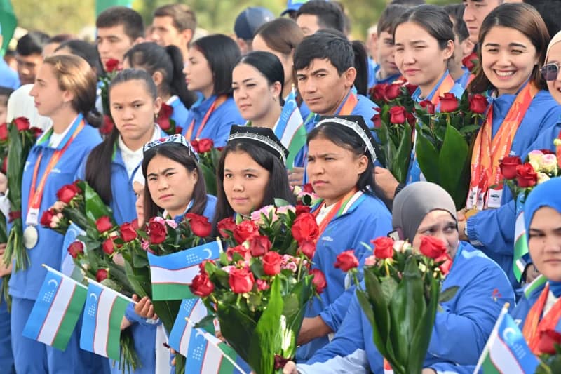 People holding bouquets of flowers and small flags in a gathering
