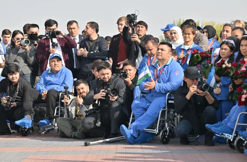 People gathered outdoors with cameras and flowers