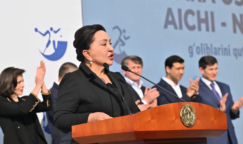 Woman speaking at a podium during an outdoor gathering