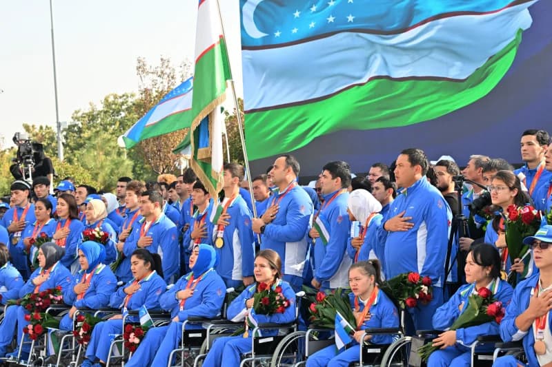 Athletes in matching blue sportswear stand together with hands placed over their chests
