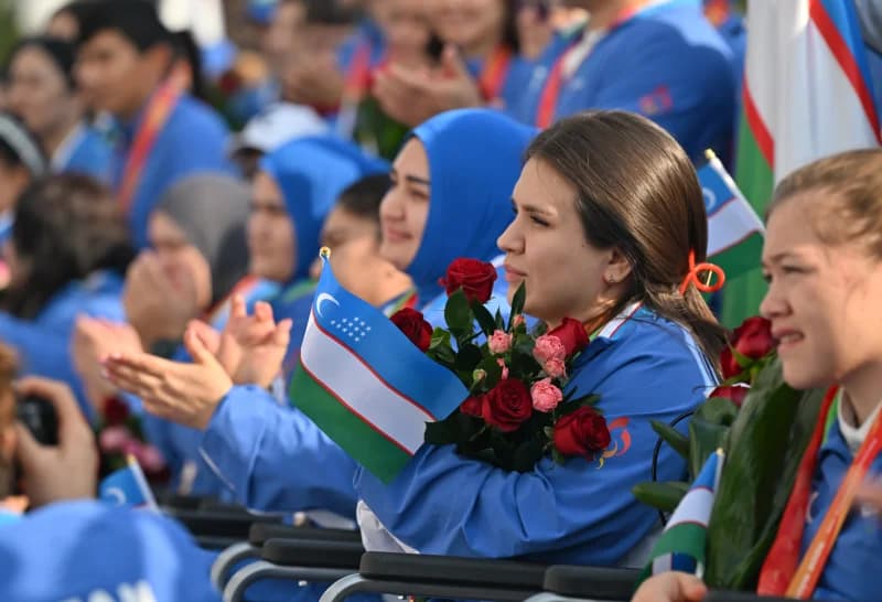 People holding small flags and flowers at an event