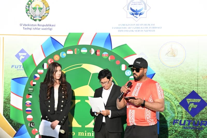 People participating in a formal event in front of a decorated backdrop